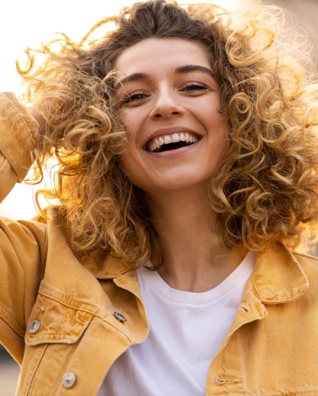 Woman with curly hair is happily smiling